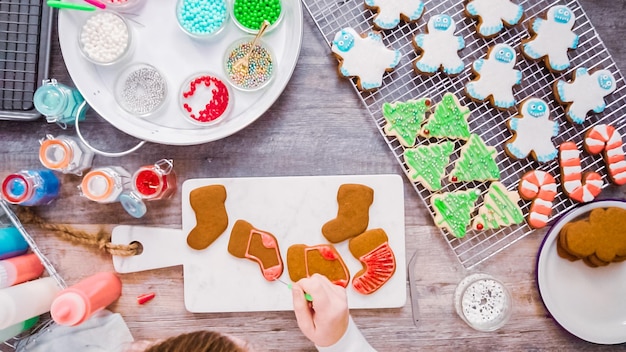 Plat leggen. Stap voor stap. Peperkoek en suikerkoekjes versieren met royal icing voor Kerstmis.