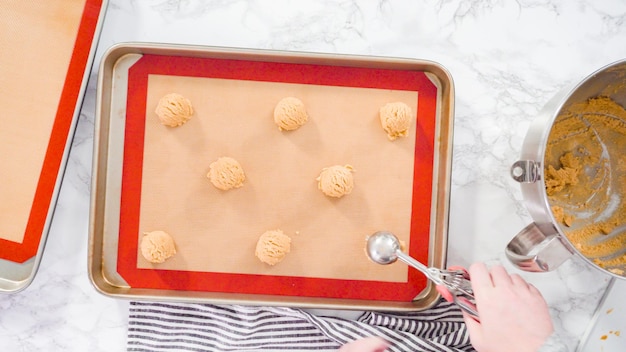 Plat leggen. Stap voor stap. Pindakaas koekjesdeeg met deegschep in de bakplaat scheppen.