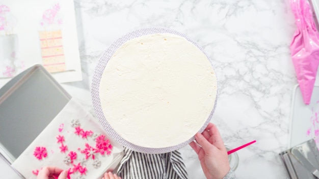 Plat leggen. Stap voor stap. Ronde funfetti taart decoreren met roze en witte fondant sneeuwvlokken.