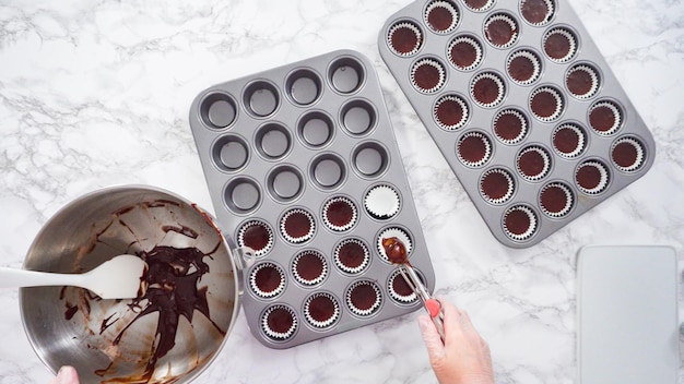 Plat leggen. Stap voor stap. Schep cupcakebeslag in mini-cupcakelijnen om mini-chocoladecupcakes te bakken.