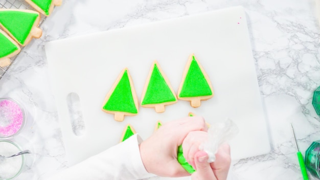 Plat leggen. Stap voor stap. Suikerglazuur Kerstboomvormige suikerkoekjes met groene royal icing.