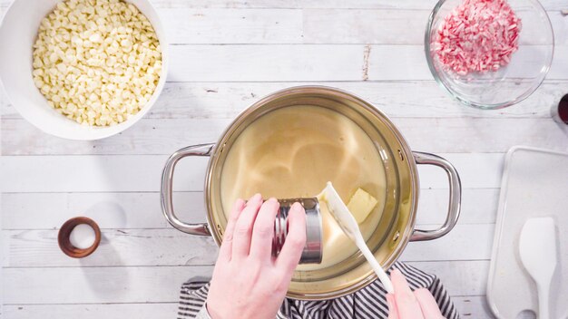 Plat leggen. Stap voor stap. Witte chocoladeschilfers smelten in de kookpot om witte chocoladefudge van suikerriet te maken.