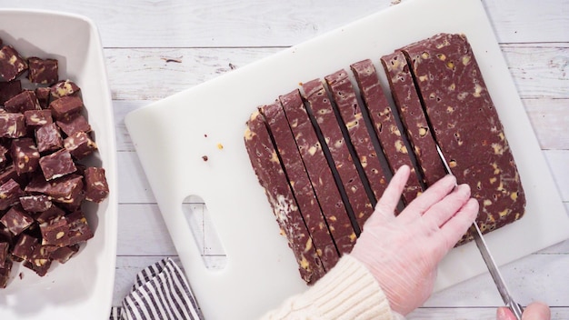 Plat leggen. stap voor stap. zelfgemaakte macadamia fudge snijden op een witte snijplank.