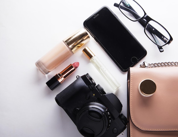 Plat leggen van beige leren damestas met cosmetica-accessoires camera en smartphone op witte achtergrond