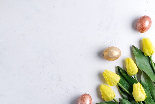 Plat leggen van gouden paaseieren met tulpen op steen marmeren achtergrond. Pasen-achtergrond of Pasen-concept.