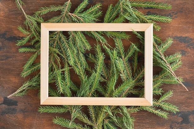 Foto plat leggen van kerstboomtakken van de kerstboom op een houten ondergrond met copyspace, van bovenaf bekijken. houten frame op de dennentakken met een plek voor tekst