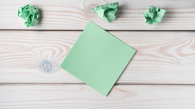 Plat leggen van lege groene sticker notitie in de buurt van verfrommelde notities op grijze houten tafel Zoeken geen idee brainstormen