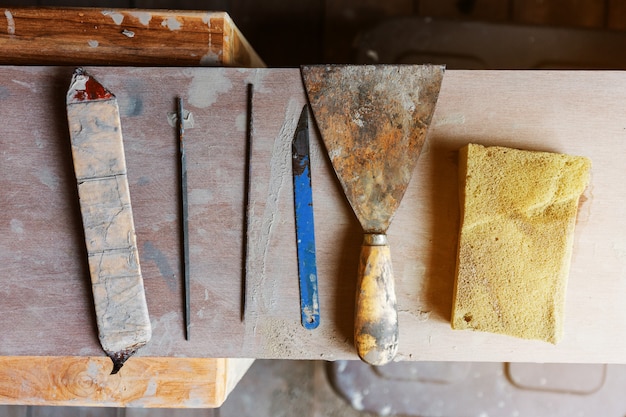 Plat leggen van zaagblad, rustieke schraper en spons voor het maken van keramisch vormaardewerk. Uitrustingen voor keramische productie. Creatie gereedschapset.