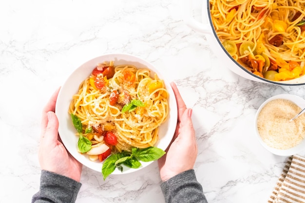 Plat leggen. Vegetarische pasta met kerstomaatjes en verse basilicum op een witte plaat.