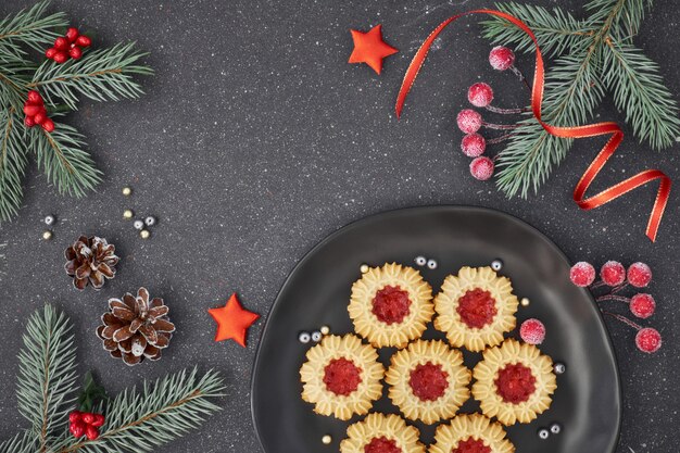 Plat met kerstdecoraties in groen en rood en jamkoekjes op donkergrijs