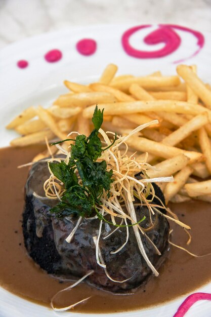 Foto plat van zwarte pudding in paddenstoel saus en friet op restaurant tafel eten