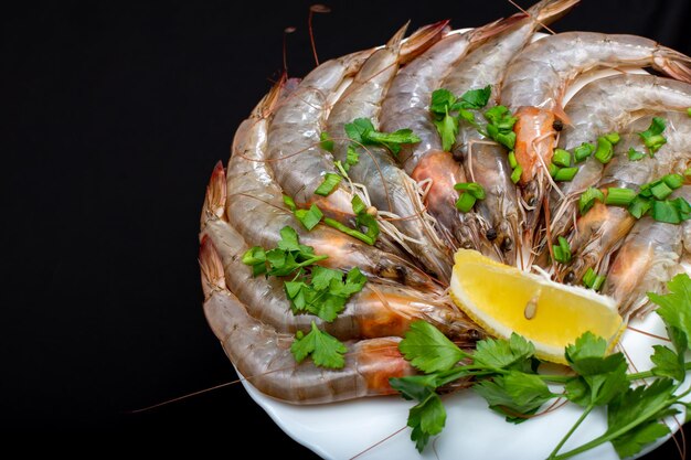 On a plate are large sea shrimp with herbs and lemon