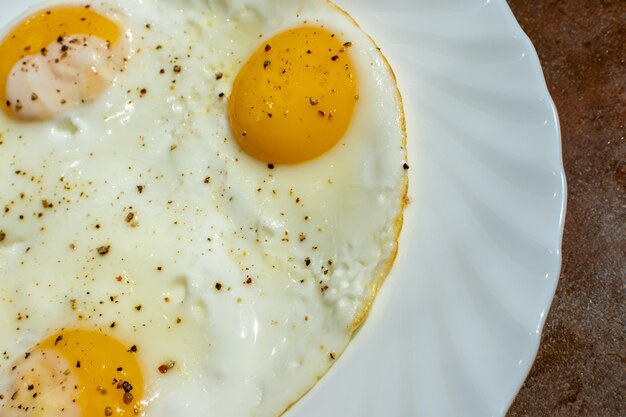 On a plate are three chicken eggs with salt and black pepper