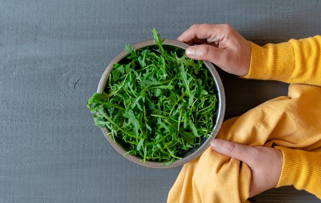 플레이트 arugula 녹색 손 노란색 회색 배경 복사 공간 fortuna 골드 색상