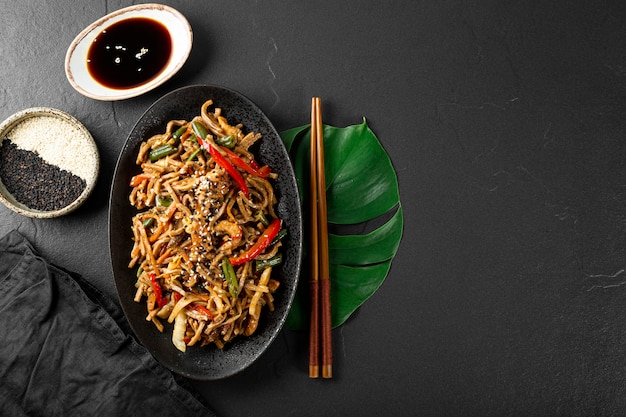 Photo plate of asian buckwheat soba noodles with vegetables mushrooms and chicken on dark background