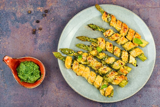 A plate of asparagus with a bowl of green pesto on the side.