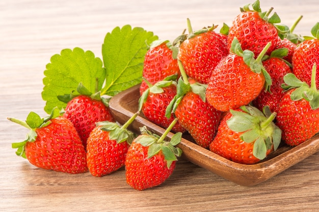 A plate of beautiful strawberries isolated on wooden background, close up.