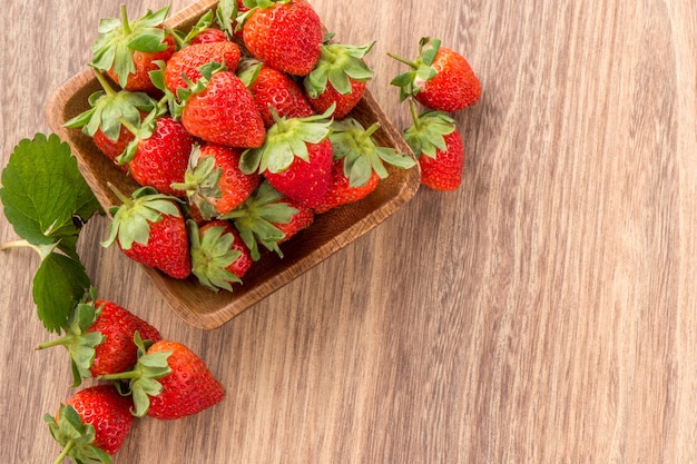A plate of beautiful strawberries isolated on wooden background, close up.