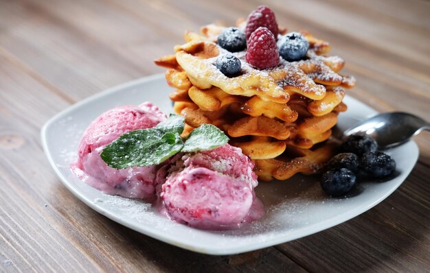Plate of belgian waffles with ice cream and fresh berries raspberries and blueberries