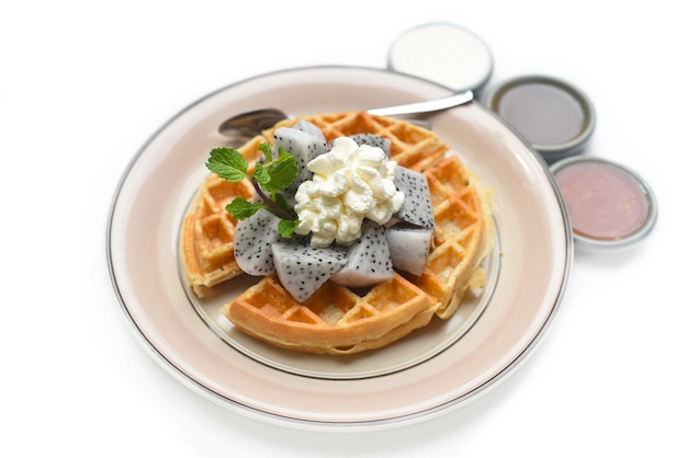 Plate of Belgium waffles with sliced dragon fruit and ice cream isolated on white background