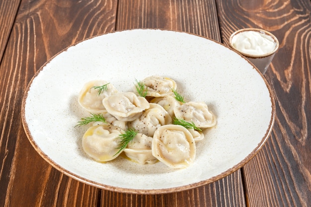 Foto piatto di gnocchi bolliti con salsa di panna acida sulla tavola di legno