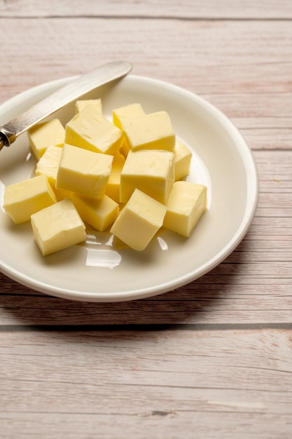 A plate of butter cubes on a wooden table