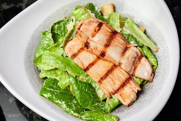 Un piatto di insalata caesar con petto di pollo e parmigiano