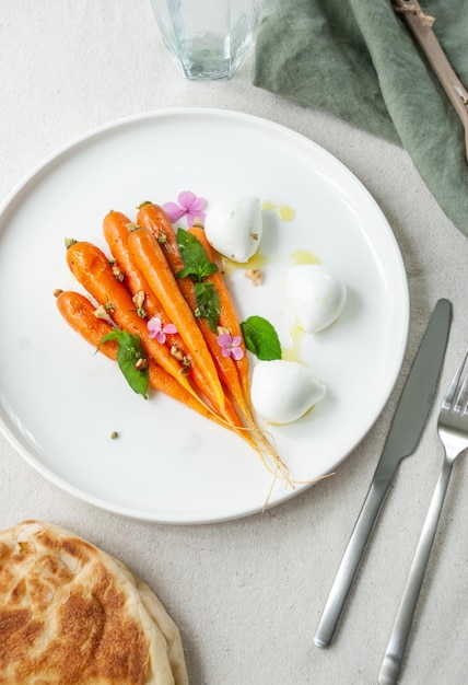 A plate of carrots with yogurt and basil on top.