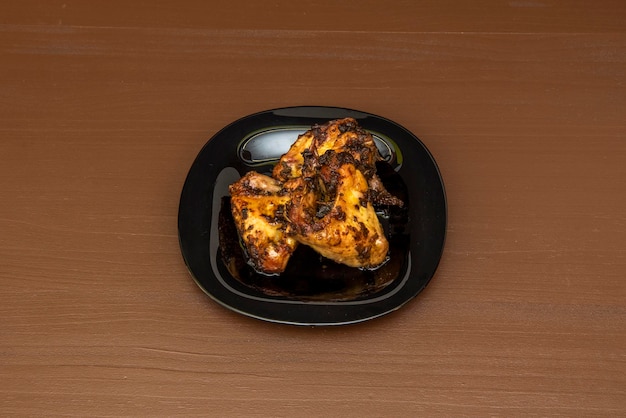 Plate of charcoal grilled wings with spicy sauce on black plate