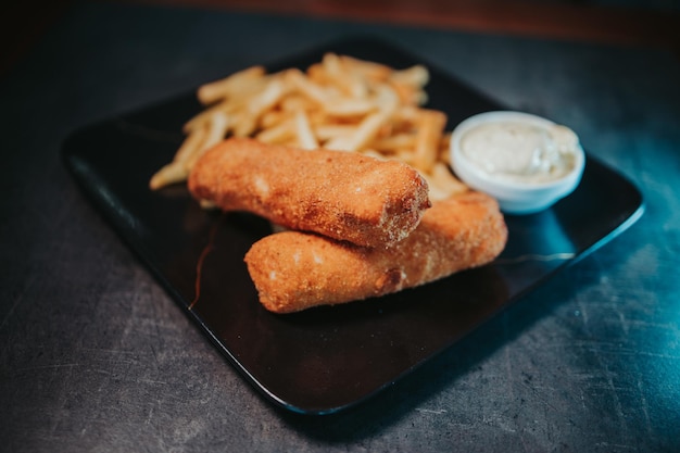 Plate of cheese sticks with fried potatoes and sauce