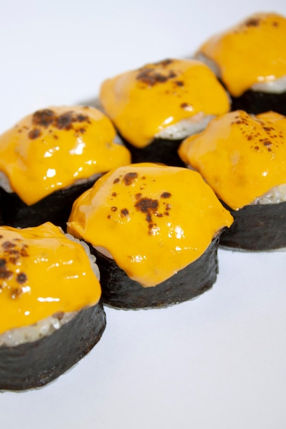 A plate of cheese sushi with a black wrapper