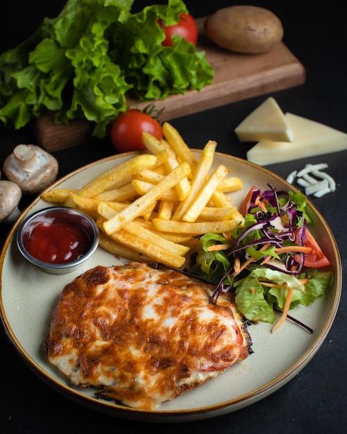 A plate of chicken and fries with a side of salad.