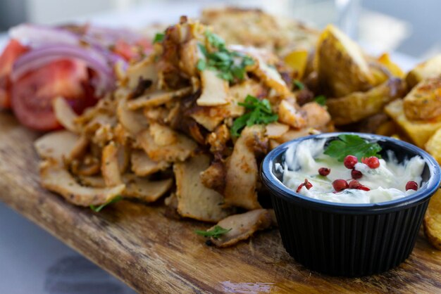 A plate of chicken gyros with potatoes and white sauce