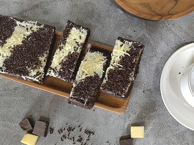 A plate of chocolate and coconut brownies with a cup of coffee on the side.