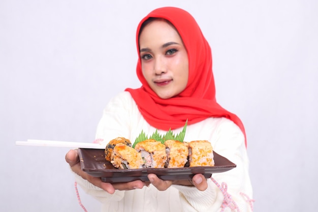 тарелка с суши, японской едой, удерживаемая красивой азиатской женщиной, улыбаясь для кулинарии