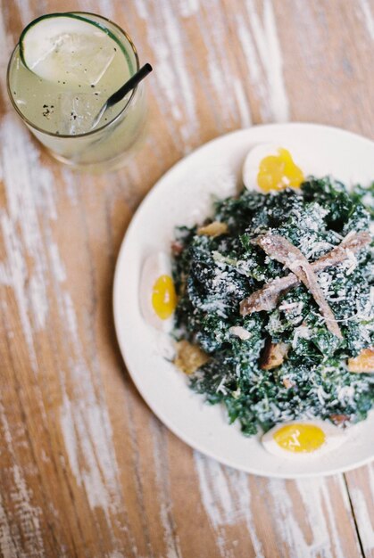 A plate of cooked vegetables and soft boiled eggs with garnishesA glass of chilled lemonade