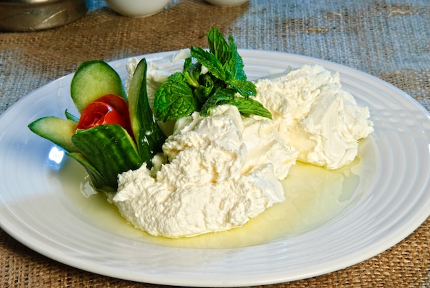 A plate of creamy hummus with olive oil and cucumbers