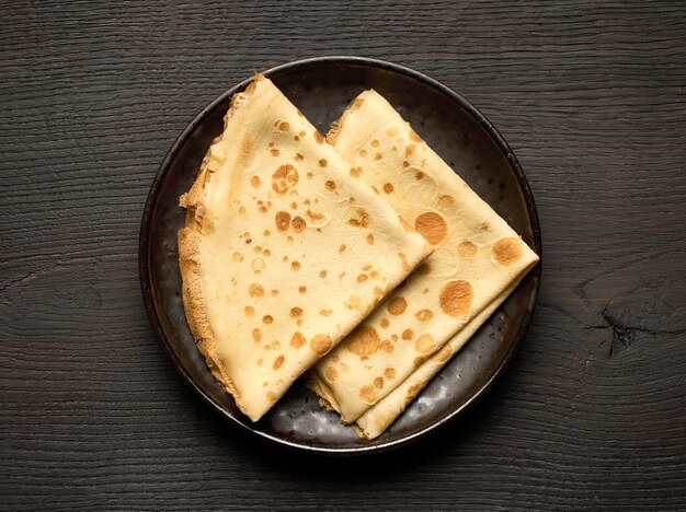 Photo plate of crepes on dark wooden table top view