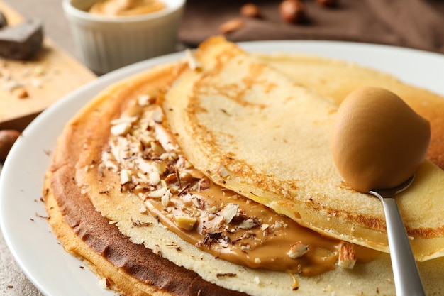 Plate of crepes with peanut butter and nuts, close up