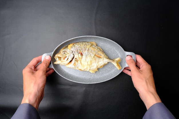 A plate of delicious fried catfish in a gray plate held by a person