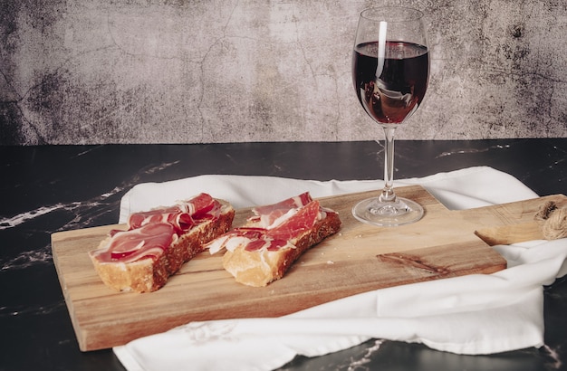 Plate of delicious Iberian ham on a wooden table background. Appetizing slices Iberian ham. Acorn-fed Iberico Ham. Pata negra, spectacular vision of sliced ham. Typical spanish food.