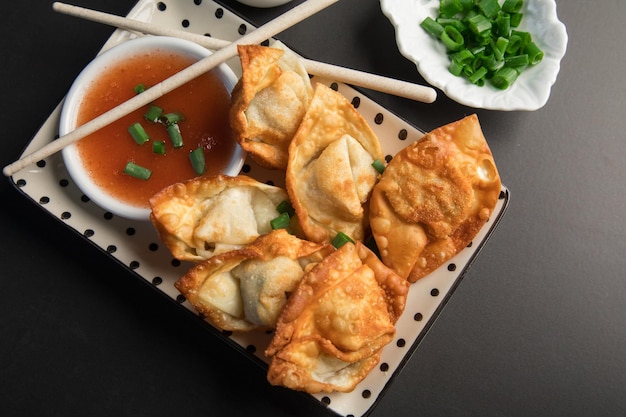 A plate of dumplings with a bowl of sauce on it