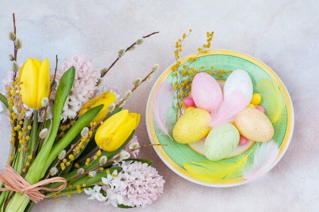 In un piatto di uova di pasqua e accanto a un mazzo di giacinti e tulipani