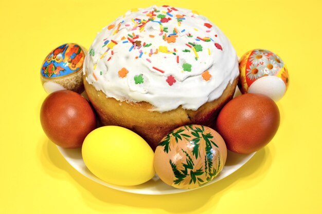 A plate of easter eggs and an easter cake with  multicolored sprinkles on it, close-up