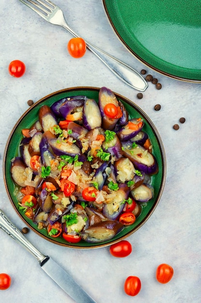 A plate of eggplant salad with tomatoes and parsley