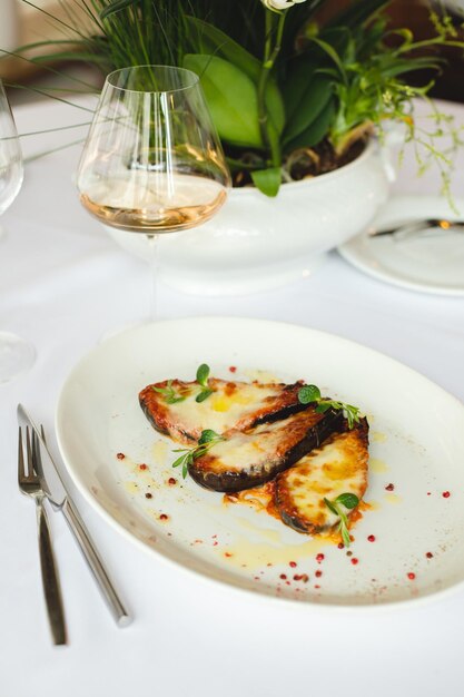 A plate of eggplant with a glass of wine in the background