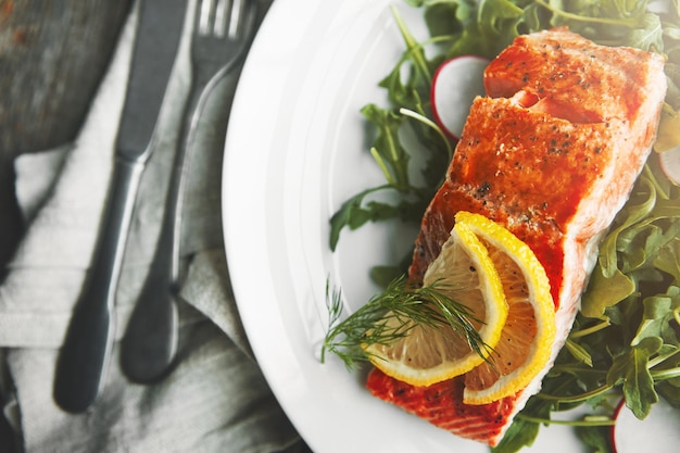 plate fish and lemon in restaurant above and food for health wellness and nutrition with fine dining salmon dinner and closeup with leaves vegetables and seafood for diet with pescatarian meal