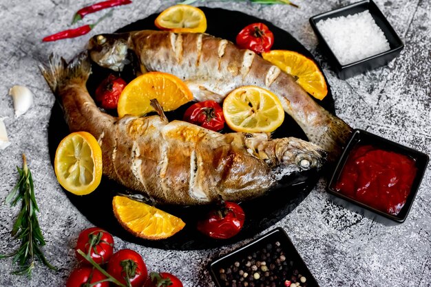 Photo a plate of fish with lemons and tomatoes on a table.