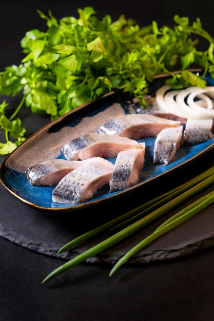 A plate of fish with onions and a bunch of green onions on the side