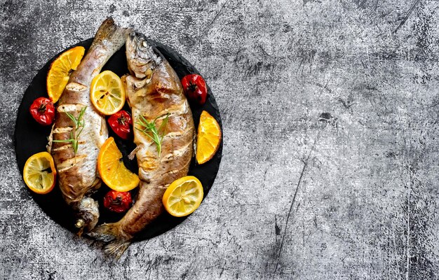 Foto un piatto di pesce con verdure su uno sfondo grigio